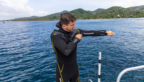 Diver donning the SCUBAPRO Definition Men's Steamer