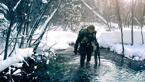 Diver standing in water with snow all around