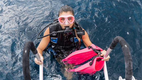 Woman diver exiting the water wearing the SCUBAPRO GO BCD