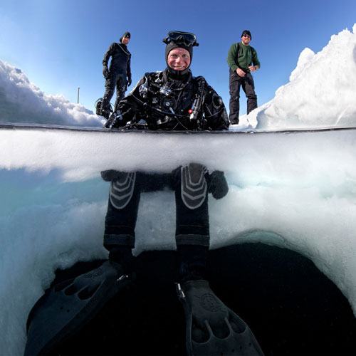 Diver sitting on snowy ice edge with SCUBAPRO Jet Fins in the water