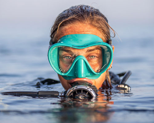 Woman diver with head above water wearing SCUBAPRO diving gear