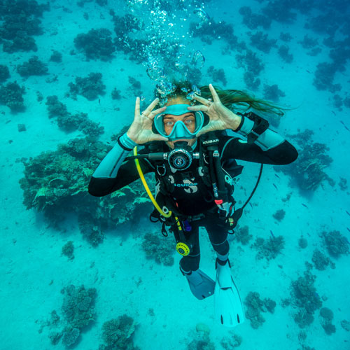 woman diver in aqua colored water wearing SCUBAPRO diving gear