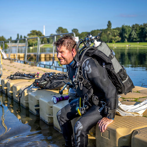 Diver sitting on a dock wearing the SCUBAPRO NovaScotia dive suit