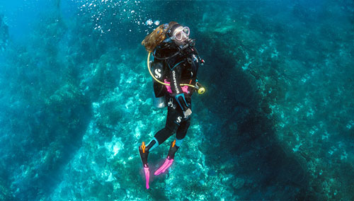 Woman diver in turquoise water wearing SCUBAPRO gear