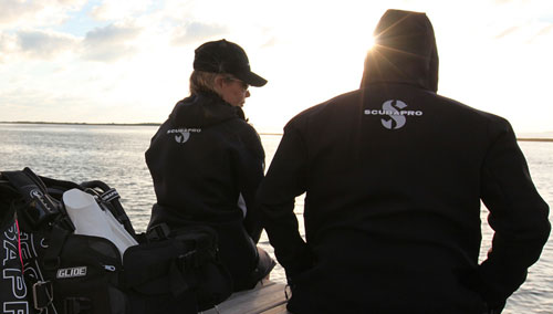 Man and woman sitting by the water in SCUBAPRO boat coats