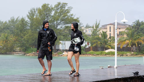 Man and woman walking on a dock in the rain wearing SCUBAPRO boat coats