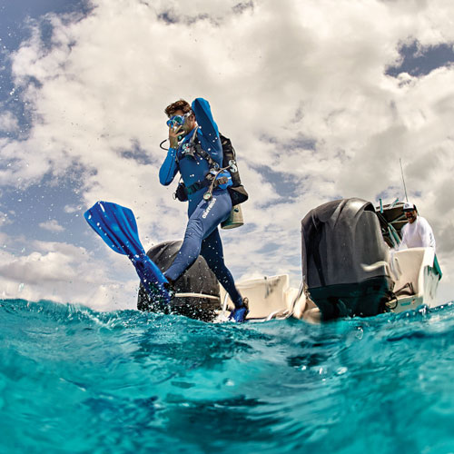 Man dressed in blue stepping off a boat into the ocean