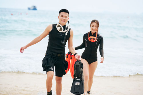 Two people walking on the beach carrying SCUBAPRO S-Tek Fins