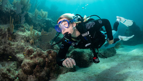 Woman diver underwater swimming along the ocean floor