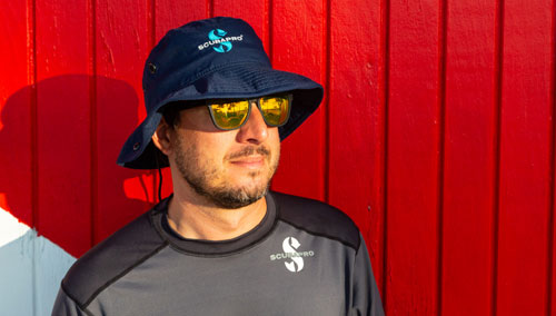 Close up of a man wearing a SCUBAPRO rashguard and hat