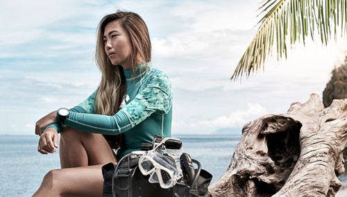 Woman sitting by the ocean wearing a SCUBAPRO rashguard