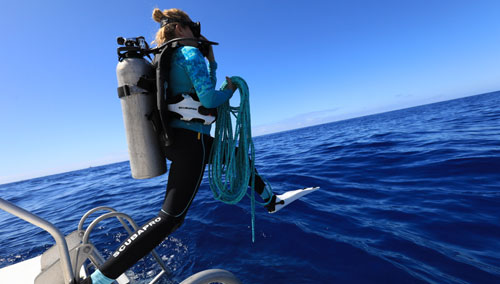 Woman diver stepping off a boat into the water