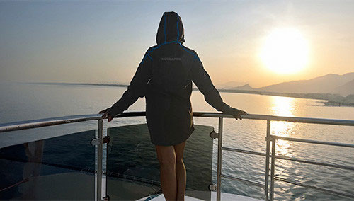 Woman standing at the boat rail watching the sunset