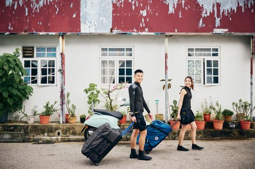 Man and woman in SCUBAPRO divewear rolling their gear down the street