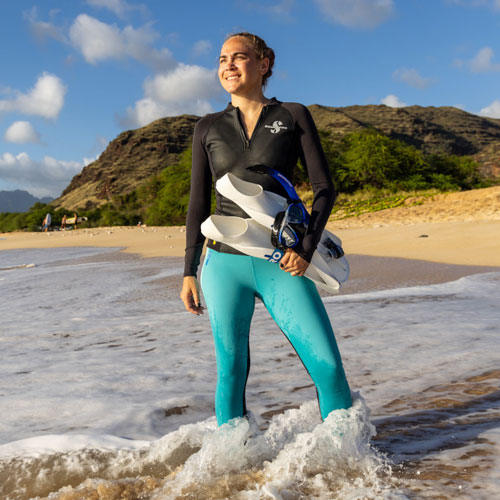 Woman standing in the surf wearing a SCUBAPRO Hybrid Top