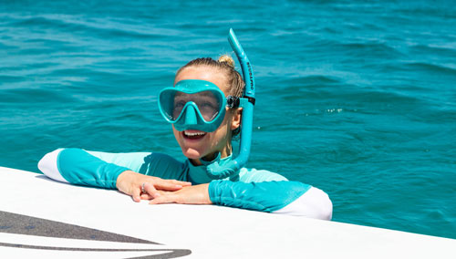 Woman in snorkeling gear holding onto the edge of a dock