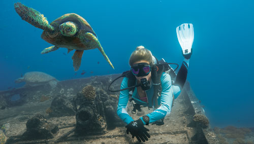 Woman diver in SCUBAPRO gear swimming with a sea turtle