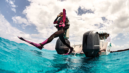 Woman diver stepping off a boat into the ocean