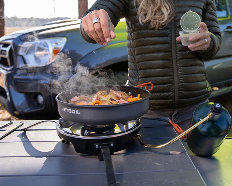 Sprinkling seasoning on cooked meat in the Jetboil HalfGen Cooking System