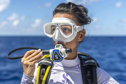 Scuba diver wearing a C370 white regulator at the ocean surface with open water in the background