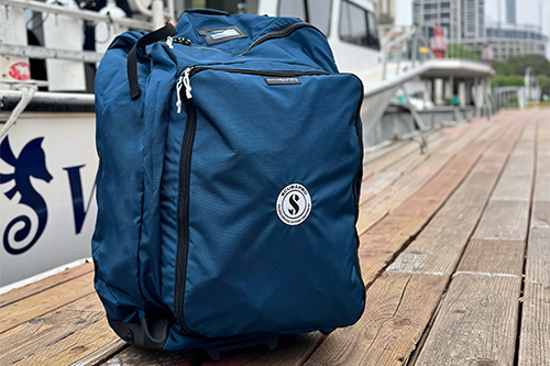 Sport Bag 125 with multiple zip compartments placed on a wooden dock by the water