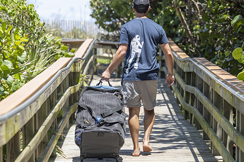 Person pulling  Sport Mesh 'N Roll 100 along a wooden boardwalk surrounded by lush greenery