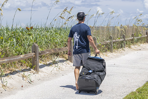 Person pulling Sport Mesh 'N Roll 100 along a sandy beach path