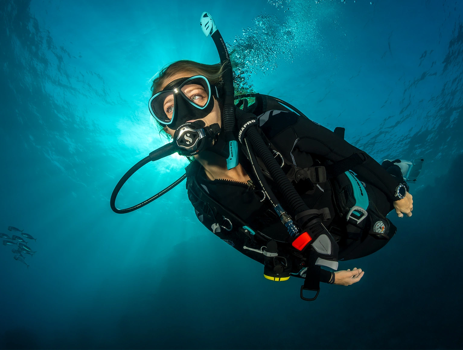Diver wearing a customized SCUBAPRO Hydros Pro 2 buoyancy compensator with color accent accessories while diving underwater.
