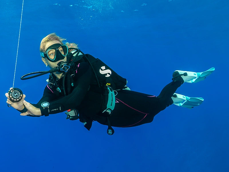 Two divers wearing SCUBAPRO buoyancy compensators swimming in open water during a dive.