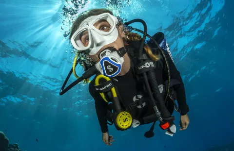 Scuba diver using C370 White Regulator with Blue Color Frame, hovering over coral reef in vibrant blue sea water
