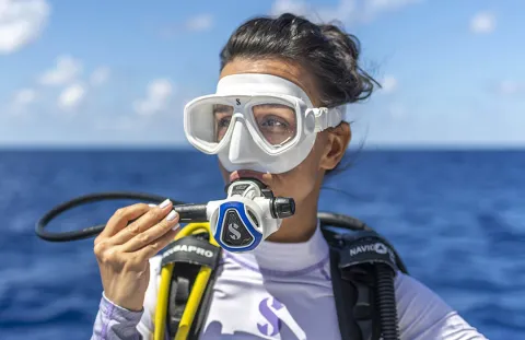 Close-up of diver using C370 White Scuba Regulator at water surface with blue sea background