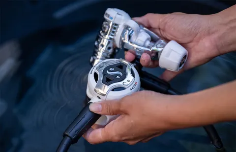 White scuba diving regulator being held following maintenance